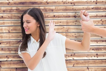 Composite image of fearful brunette being grabbed by the hand