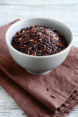 Long black rice in a clay bowl on napkin