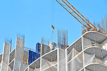 Crane lifting concrete mixer container against blue sky