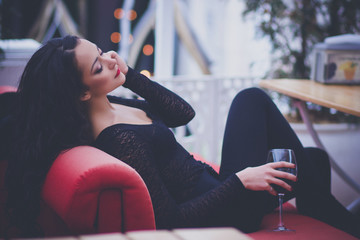 Beautiful woman with long hair drinking red wine in a restaurant - obrazy, fototapety, plakaty