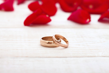 Wedding rings and wedding bouquet of red roses petals.