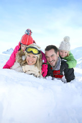 Cheerful family laid down in snow ground