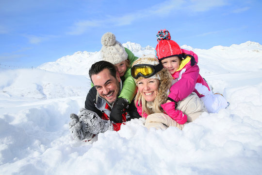 Portrait of happy family laying down in snow