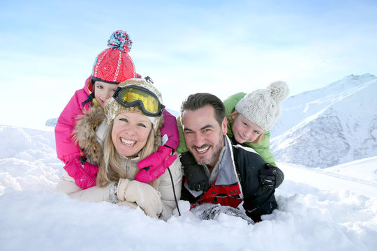 Cheerful family laid down in snow ground