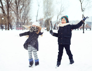 boy and girl having fun with the snow in winter park