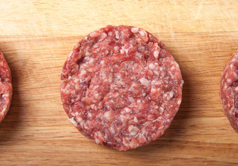 Raw cutlet of minced meat on a wooden cutting board
