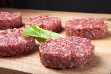 Raw cutlet of minced meat on a wooden cutting board