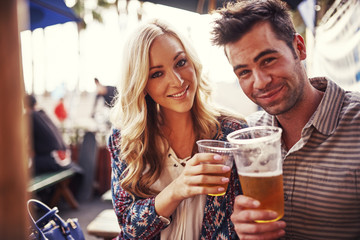 attractive couple drinking beer at outdoor restaurant - obrazy, fototapety, plakaty