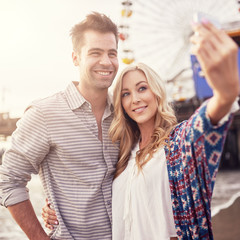 romatic couple taking selfie in front of santa monica