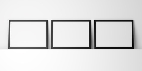 three blank black photo frames on white shelf