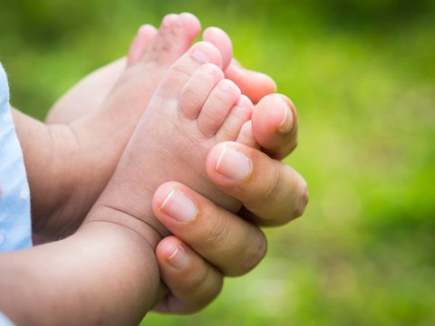 mother holding baby feet with natural background