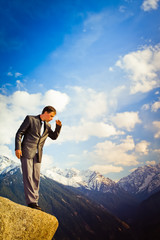 Young businessman looking down from the mountain top