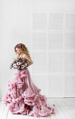Hairstyle. Girl posing in pink dress full length. Studio