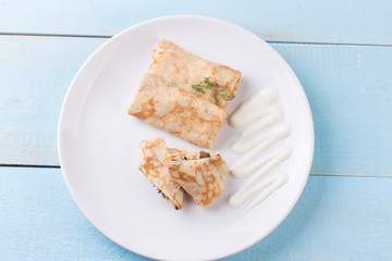 Stuffed crepes topped with sour cream.