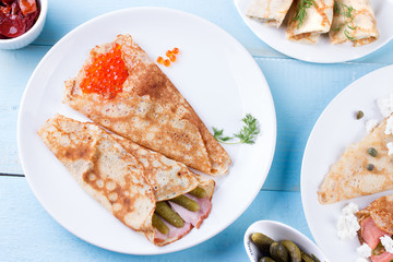 Thin pancakes, crepes with red caviar, salmon, pickled cucumbers