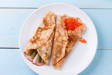Thin pancakes, crepes with red caviar, pickled cucumbers and