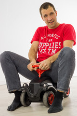 Mann spielt mit Bobbycar