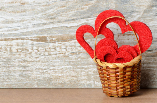 Körbchen mit roten Herzen vor Holz Hintergrund als Valentinstag