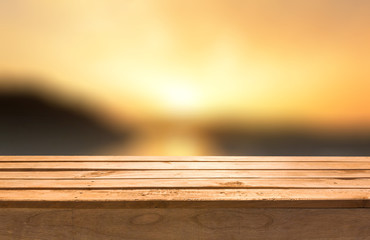 Empty wooden deck table on sunset abstract background.