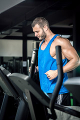 Fototapeta na wymiar Young man running at treadmill in gym