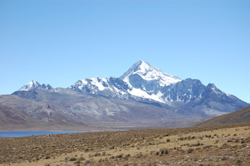 High elevation plain and lake under a looming snow capped mountain, Andes Mountains, Bolivia, South America