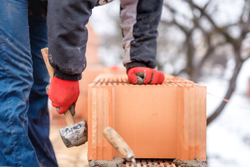 Detail of worker, bricklayer construction engineer fixing bricks