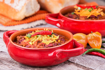 Meat and bean chili garnished with shredded cheddar cheese