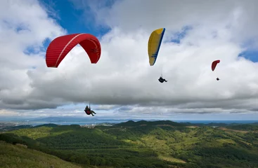 Fototapete Luftsport Drei Gleitschirmfliegen über dem grünen Tal.