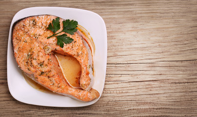 Salmon steak on plate over wooden background