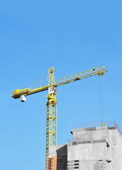 Crane and building construction site against blue sky