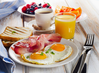 Frühstück mit zwei Spiegeleiern, Toast, Orangensaft und Kaffee.