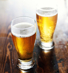 fresgly poured beer in mugs on top of wooden table