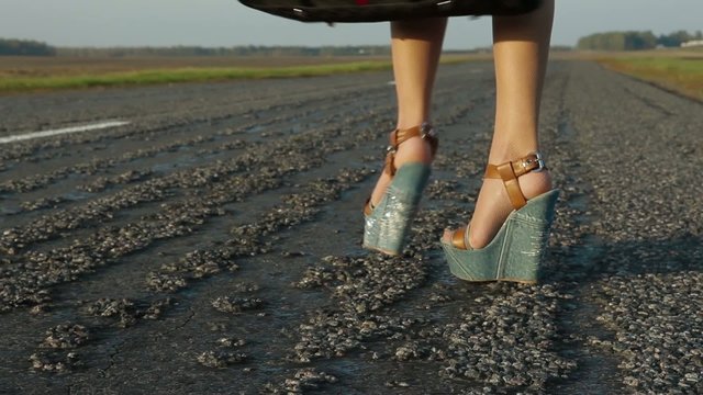 Women's feet are on the road hitch-hiking the car