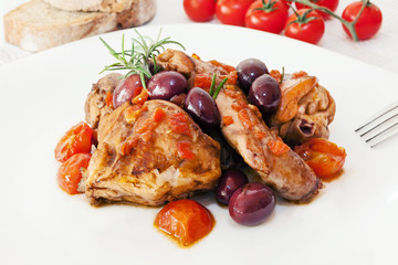 Rabbit into pieces, cooked in a pan with tomatoes, olives,