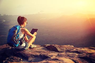 woman hiker taking photo with digital tablet at mountain peak 
