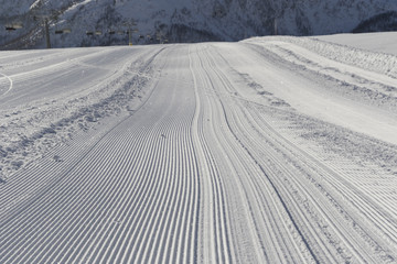 Fresh snow groomer tracks on a ski piste