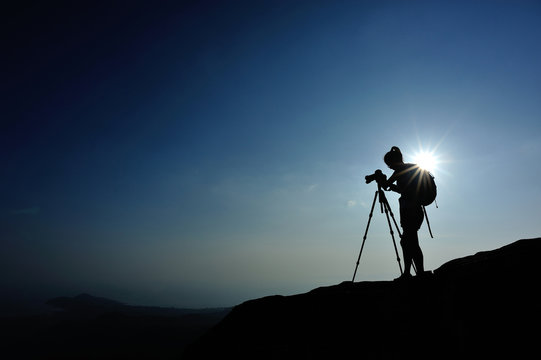 woman photographer taking photo on sunset seaside mountain peak