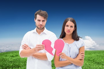 Upset couple holding two halves of broken heart