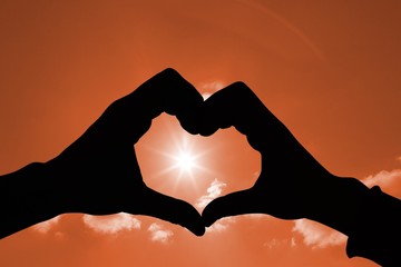 Composite image of couple making heart shape with hands