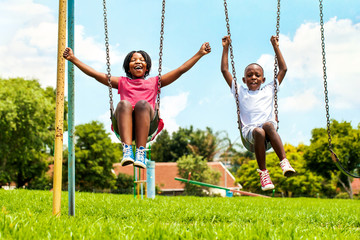 African kids playing on swing in neighborhood. - obrazy, fototapety, plakaty