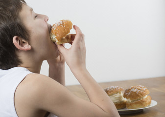 Young boy munching on a cream bun