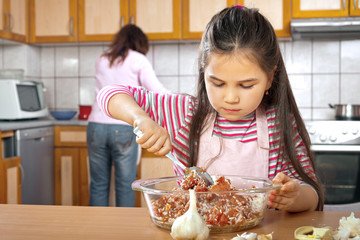 Mother and daughter prepare meat for lunch