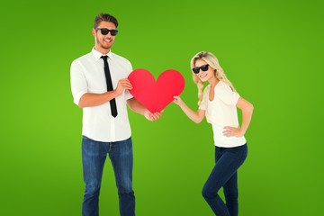 Composite image of cool young couple holding red heart