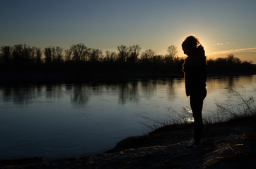 Young girl at sunset on the river bank