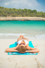 Young woman sunbathing on tropical beach.