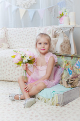 Fototapeta premium Little girl sitting on small bag with flowers