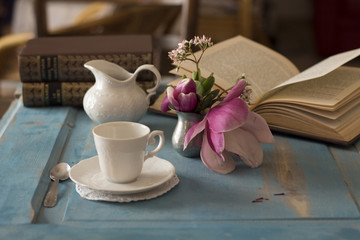 A pretty coffee cup and creamer on old wooden table.
