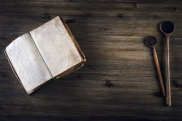 Fototapeta premium Old open book without text old wooden spoon on a wooden table