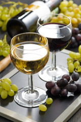 white and red wine in glasses, grapes in the background