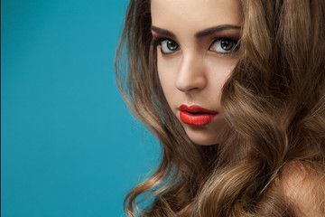 Fototapeta premium Woman with long hair on a blue background. Close up